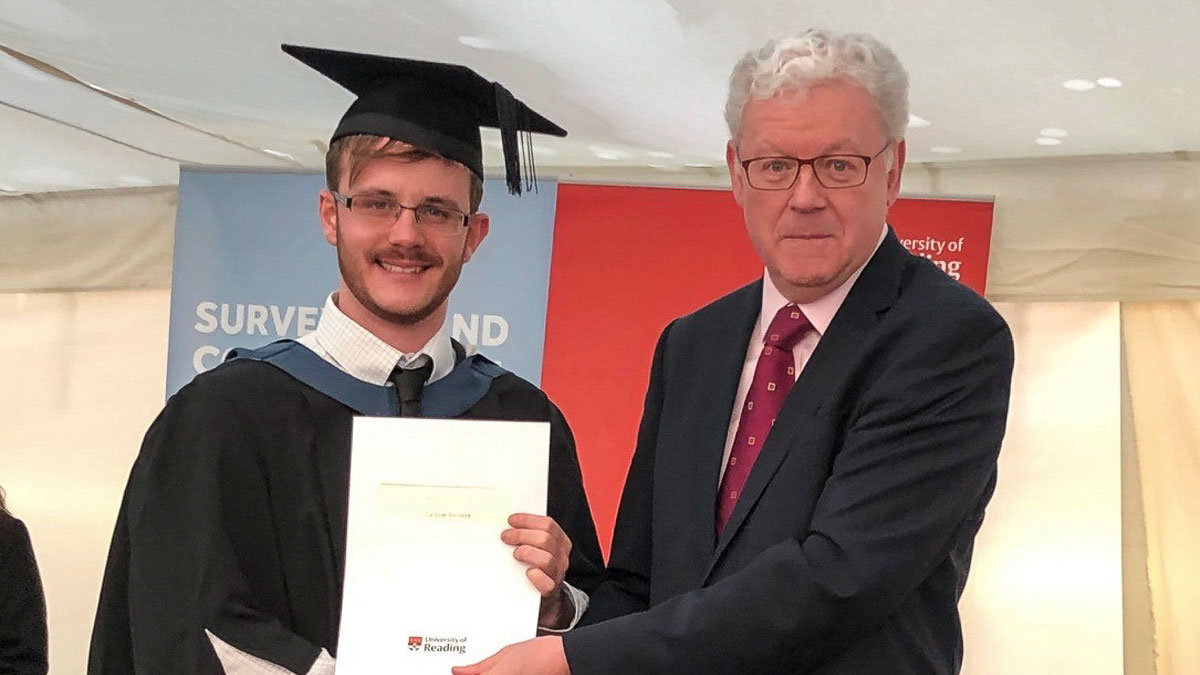 Callum Forsyth in cap and gown shaking hands with another man and holding a piece of paper