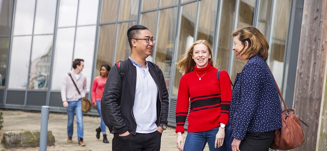 Three postgraduate students standing outside Henley Business School