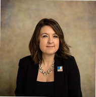 Female wearing a black blazer, with a short dark bob smiling at the camera