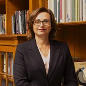 Head shot of women wearing a blazer and glasses with short brown hair looking at camera