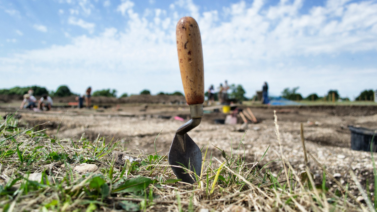 A trowel sticking out of the earth in the middle of an archaeological dig site.
