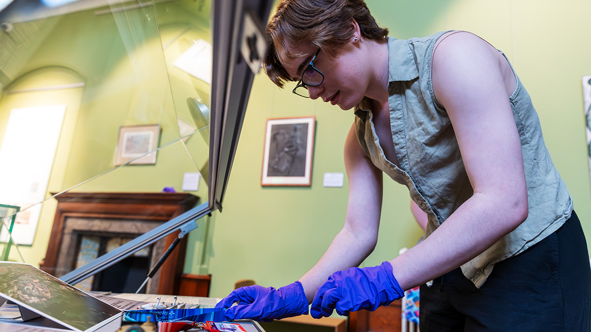 Museum studies student handles exhibits with protective gloves
