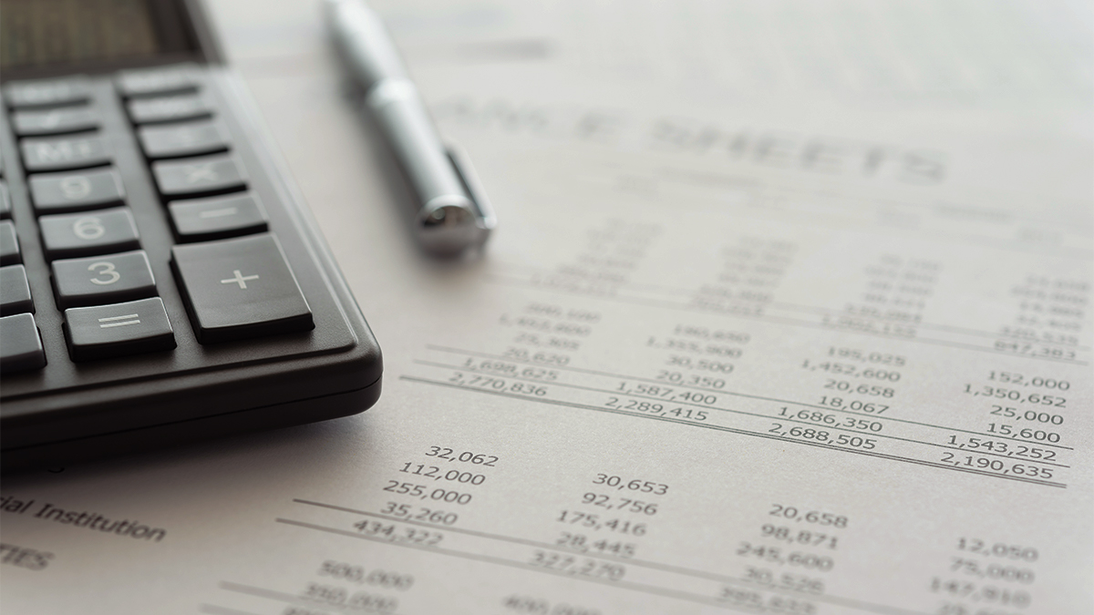 Close up of calculator, pen and a piece of paper with financial information