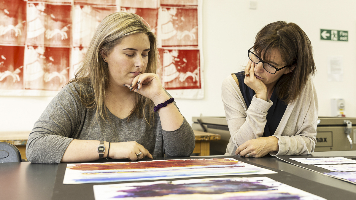 Two students reviewing artwork