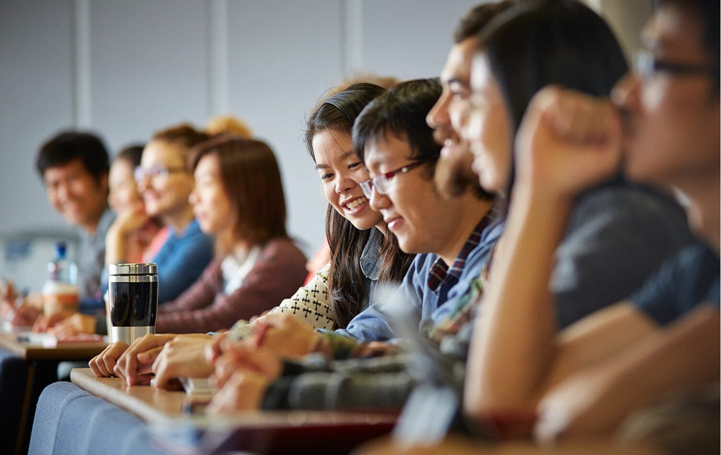 Students listening and taking notes during a university lecture.