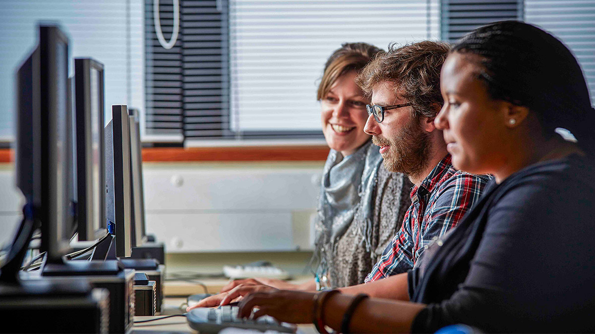 Three students working on computers in a computer lab