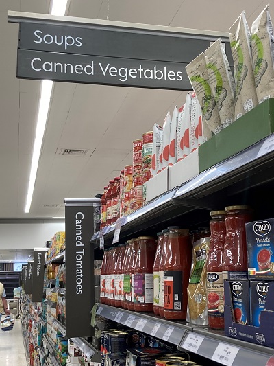 Supermarket aisle with notices displayed on top about the content of the aisle and on the sides of the racks about the content in each shelf