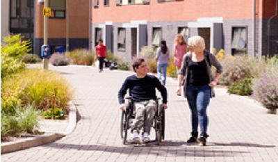 student in wheelchair with staff member on campus