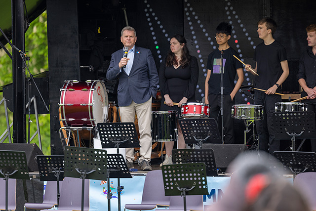 Vice Chancellors delivering a speech on stage with the band