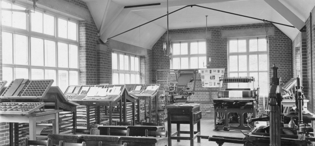 Black and white photograph of an early art studio containing printing and typesetting machines 
