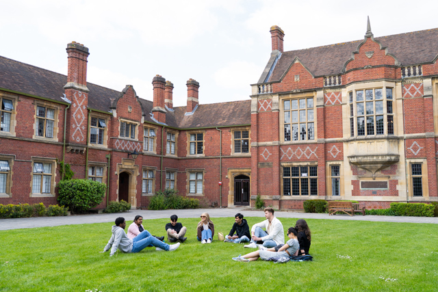 Students sat on grass in front of halls