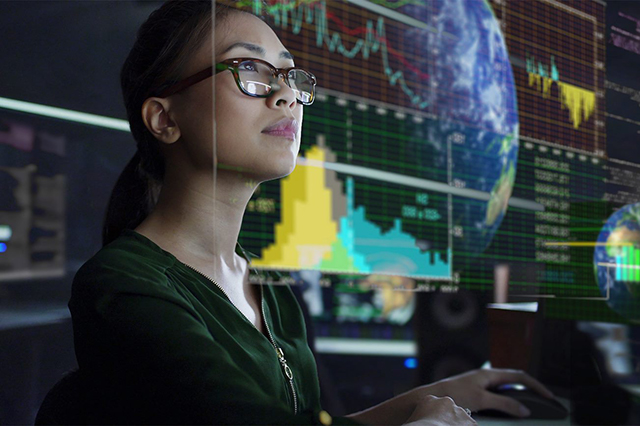 Woman working at a computer with a digital climate model in the background