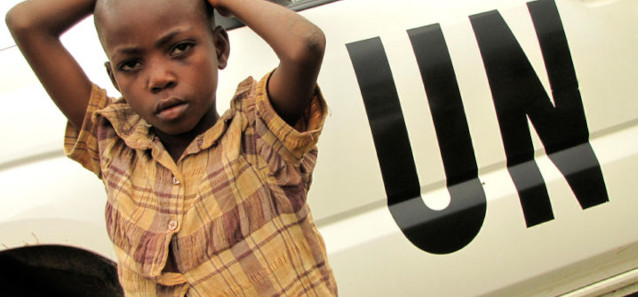 A child standing in front of a truck with "UN" painted on the side in black. 