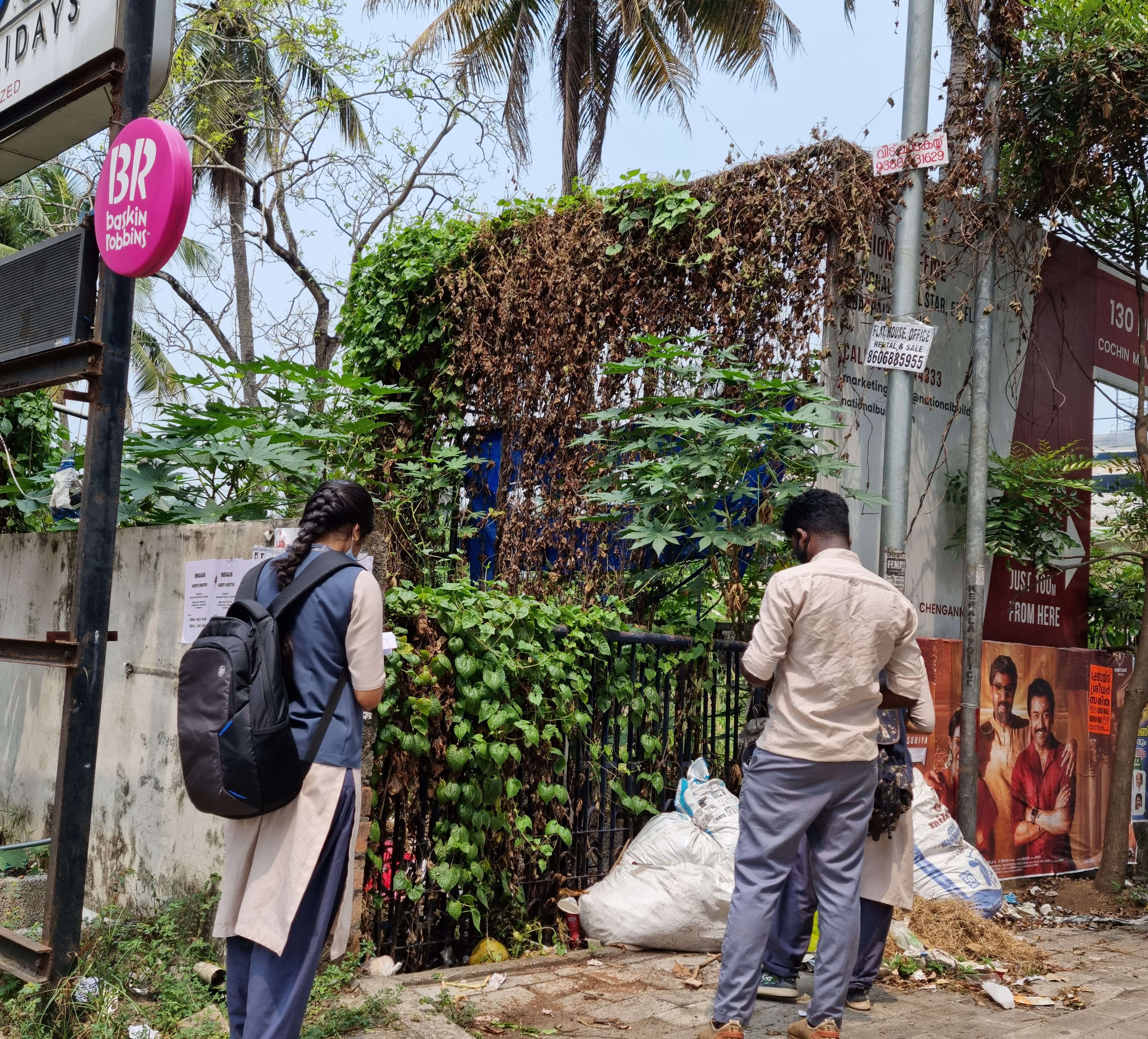 A man and woman examine a derelict, overgrown building in Kochi, India.
