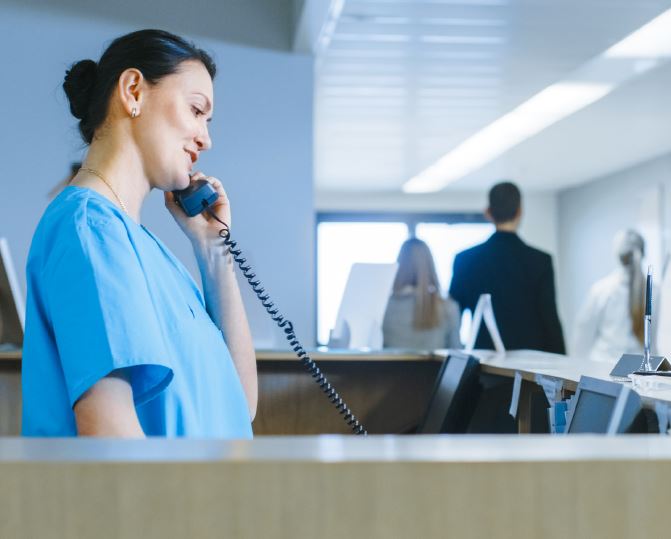A nurse speaking on the phone in a hospital ward.
