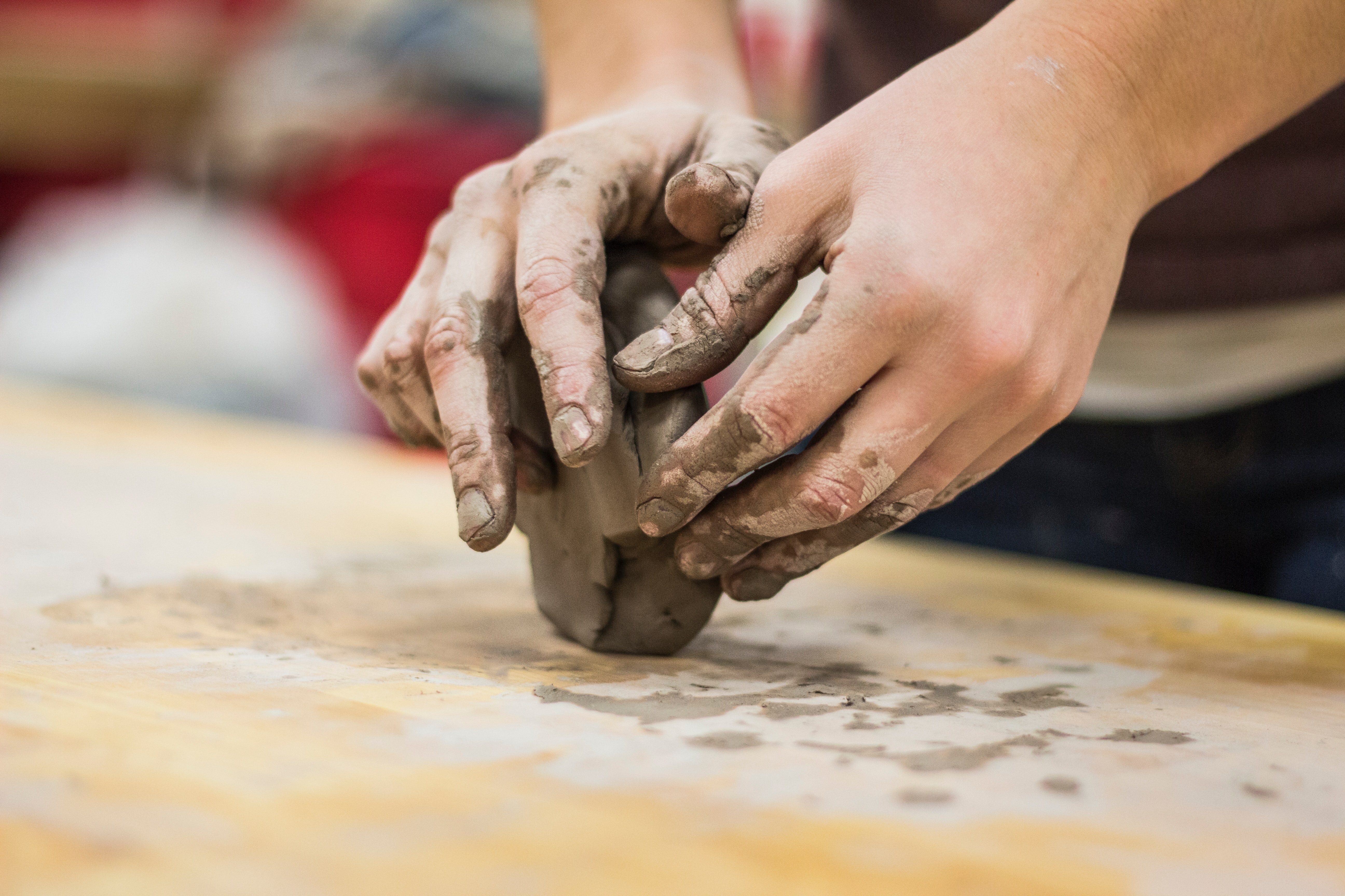 An artist's hands moulding wet clay.