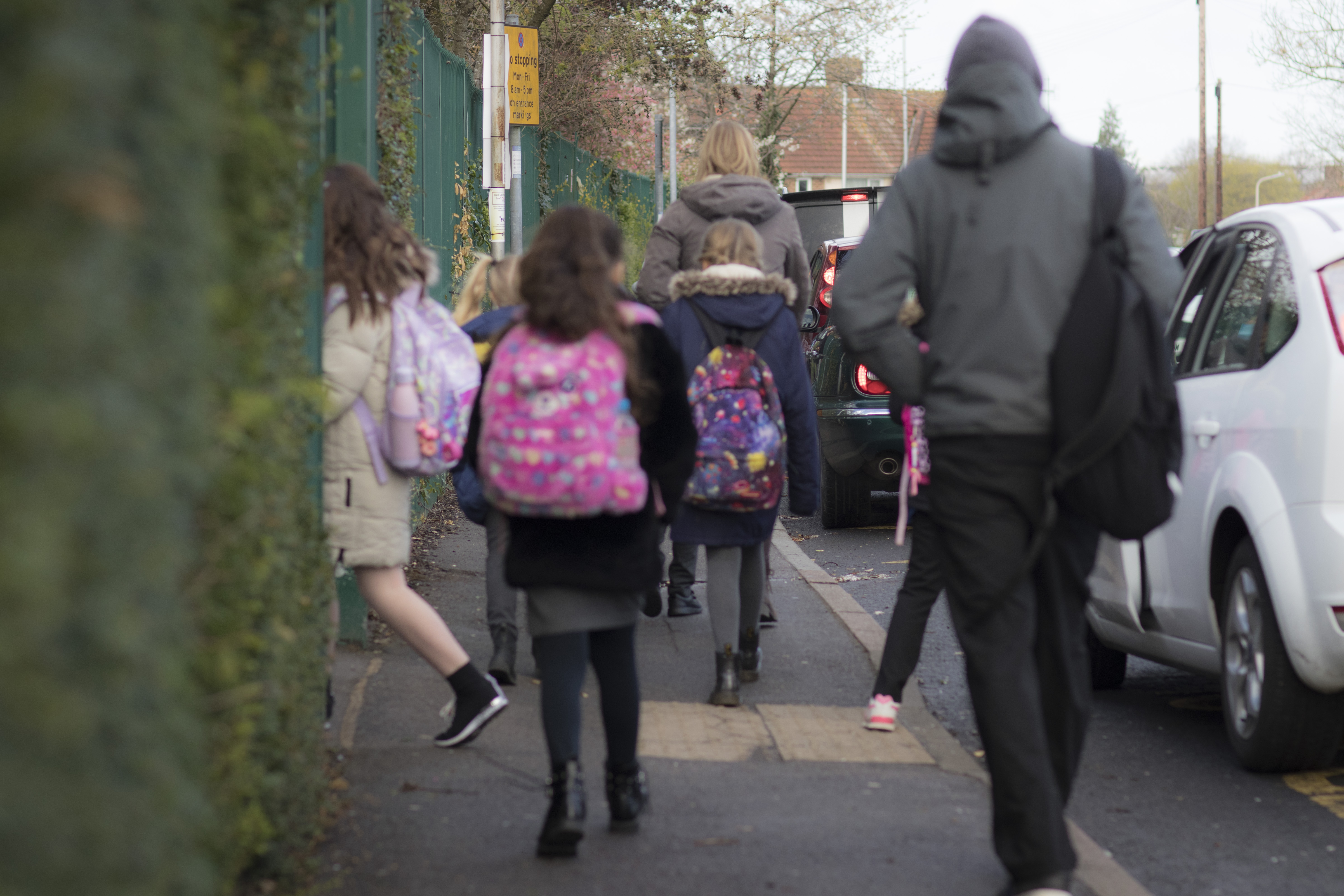 Adults accompanying a small group of children as they walk to school.