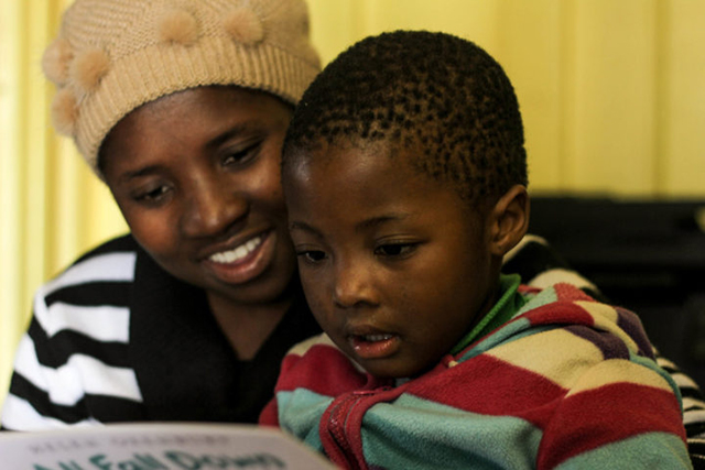 A mother and a young child read a book together