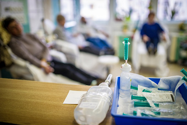 Patients in a hospital with a syringe of medication in the foreground