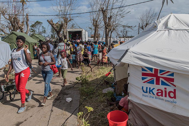 People walk near a UK aid tent