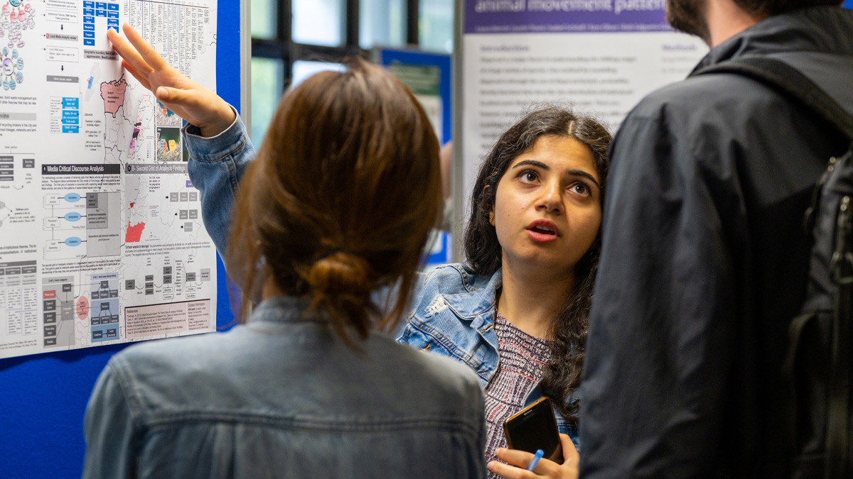 A PhD student presenting her research with a poster