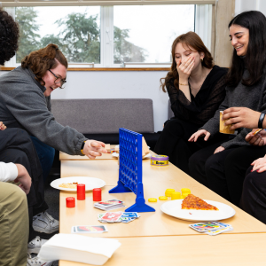 Students playing Jenga and eating pizza at a Student Life Event. 