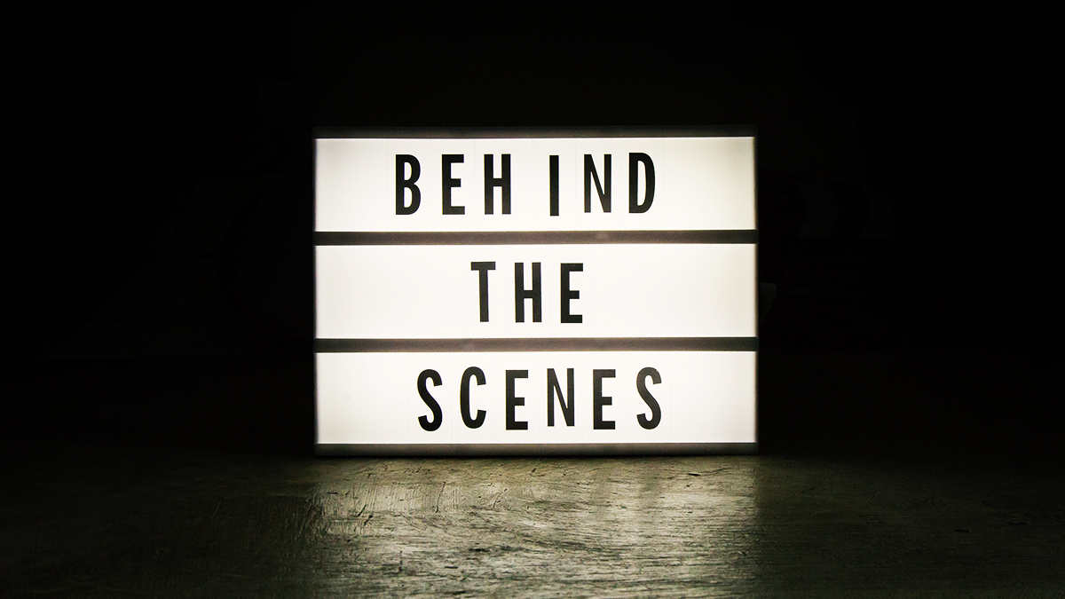 Lightbox sign that says 'behind the scenes' in a dark room