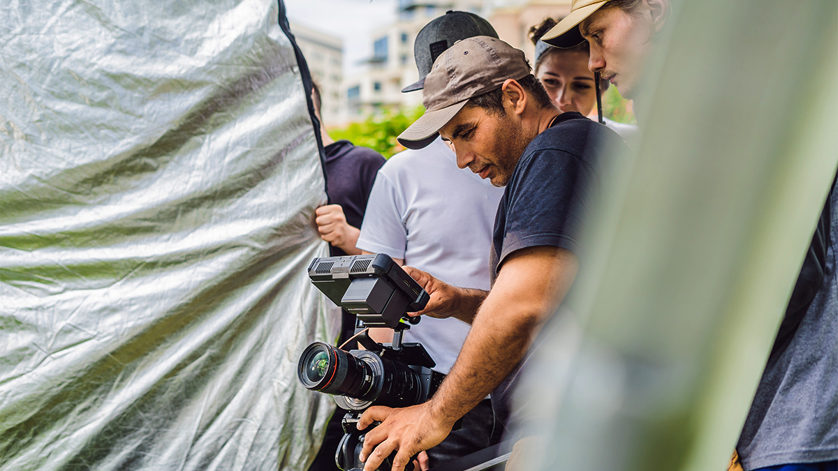 Film crew looking through camera with light blockers