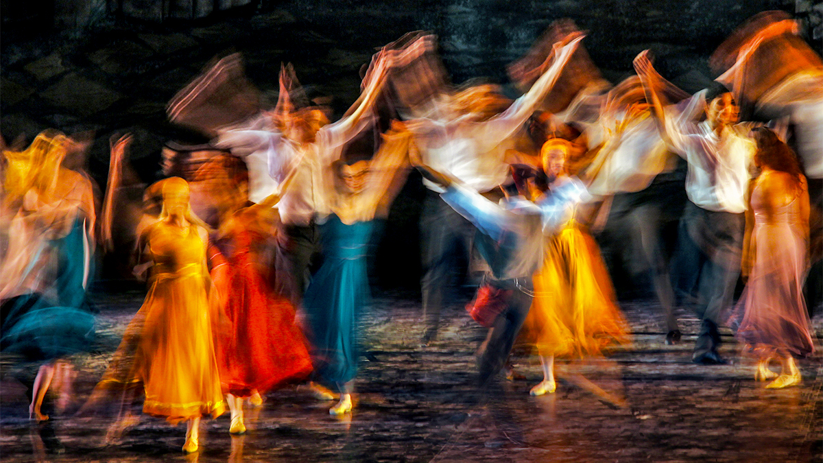A blurred image of dancers performing on a theatre stage
