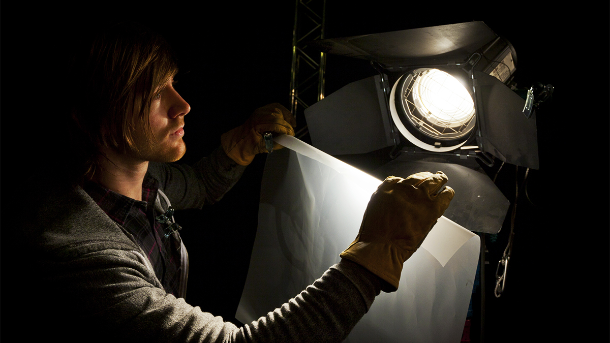 Student working in the dark in front of a spotlight