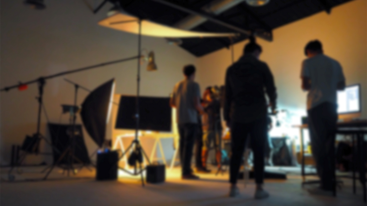 Students setting up the lighting for their film shoot in a studio space. 
