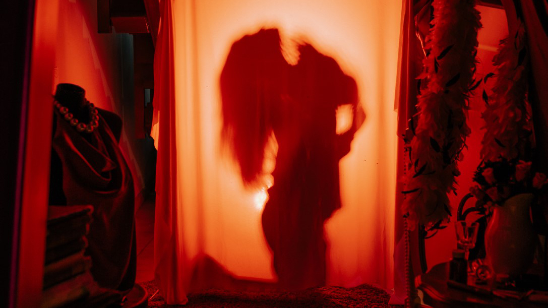 Silhouette of a woman behind a curtain with a light source behind her