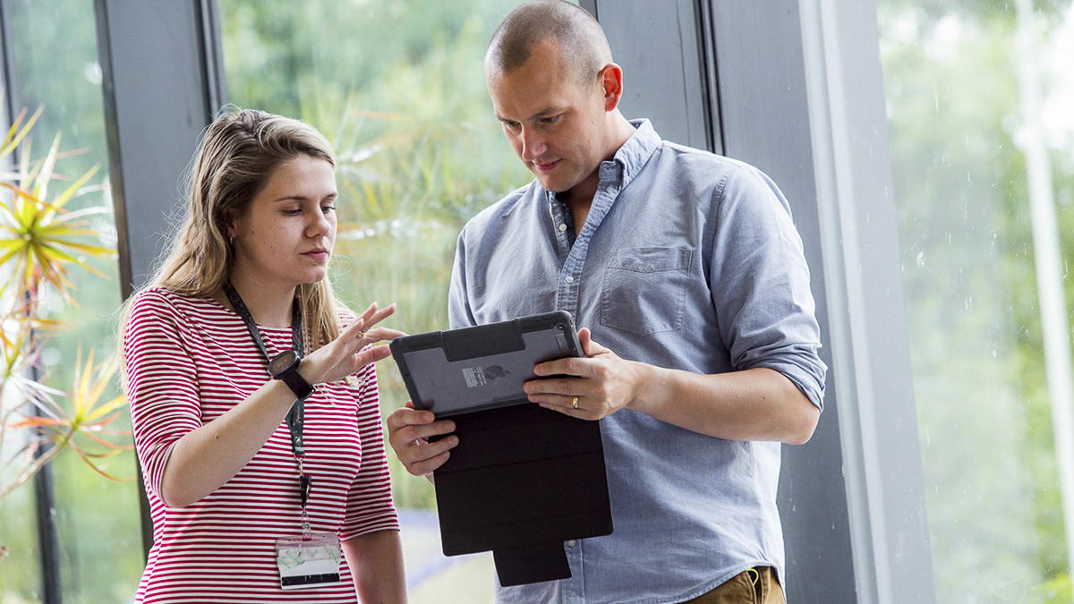 An academic and student looking at a computer tablet together