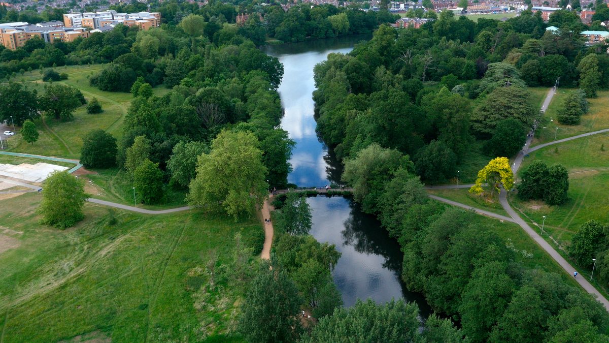 Aerial view of a river winding through a green landscape with trees and open fields.