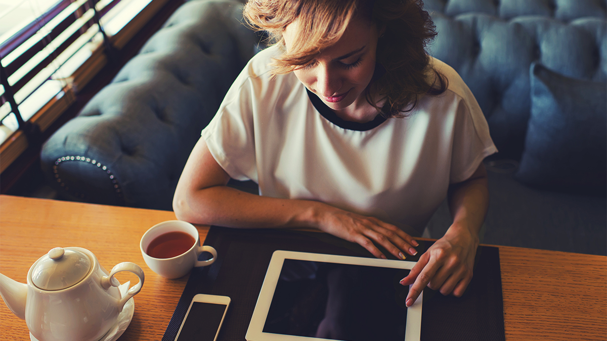 Student at a cafe drinking tea and using tablet