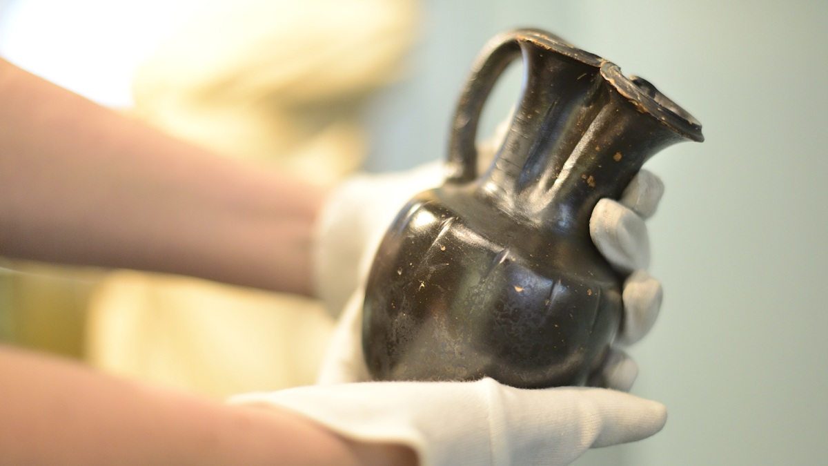Close up of gloved hands holding Greek pot