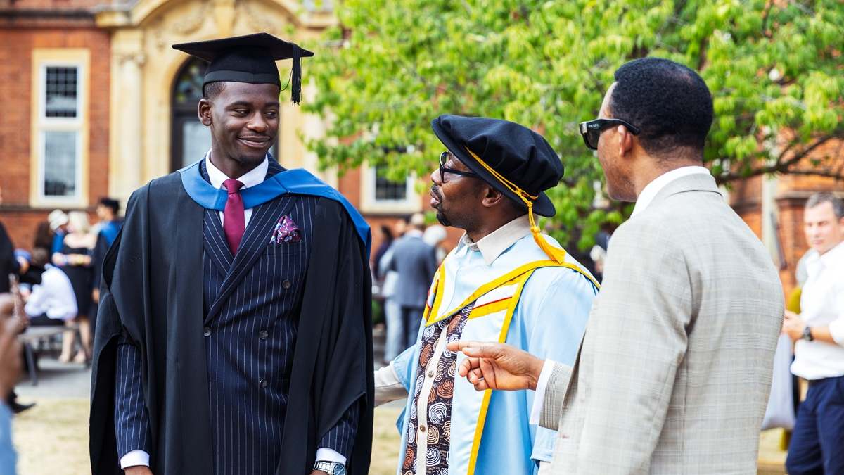 Student at Graduation talking to an academic and visitor