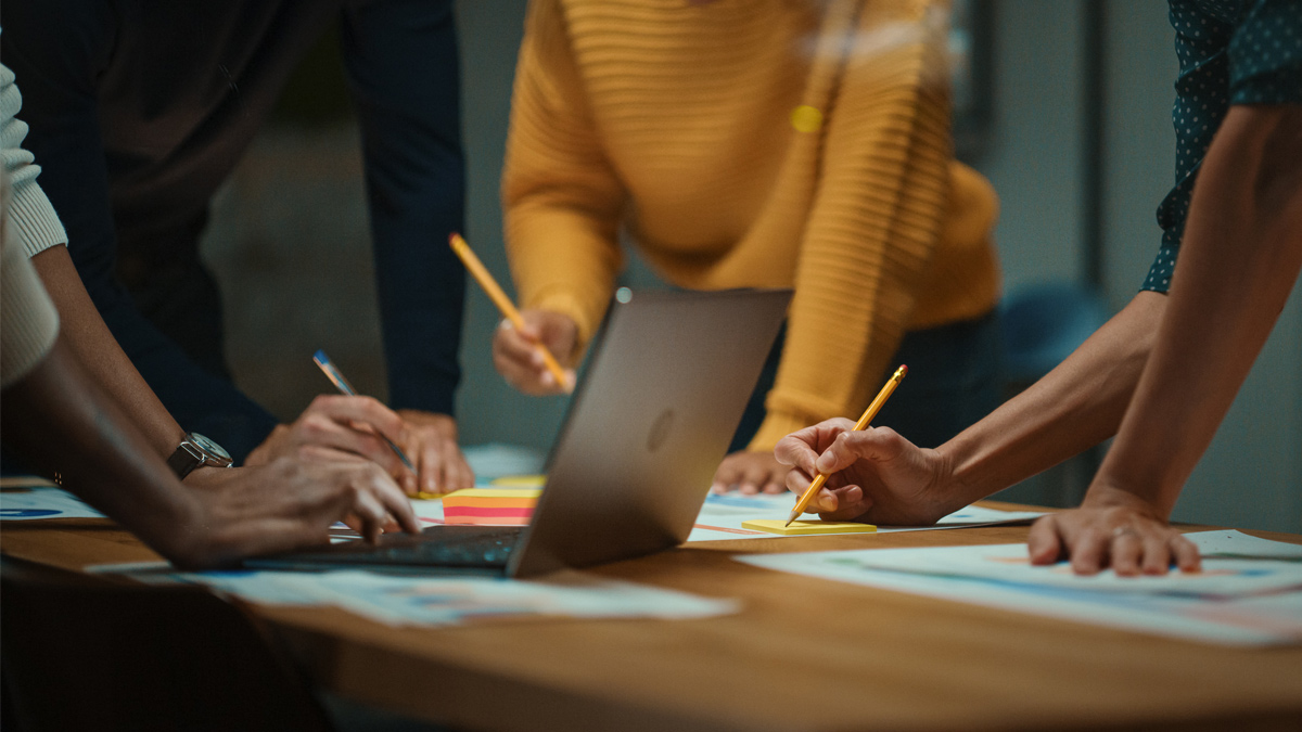group meeting around a laptop and taking notes