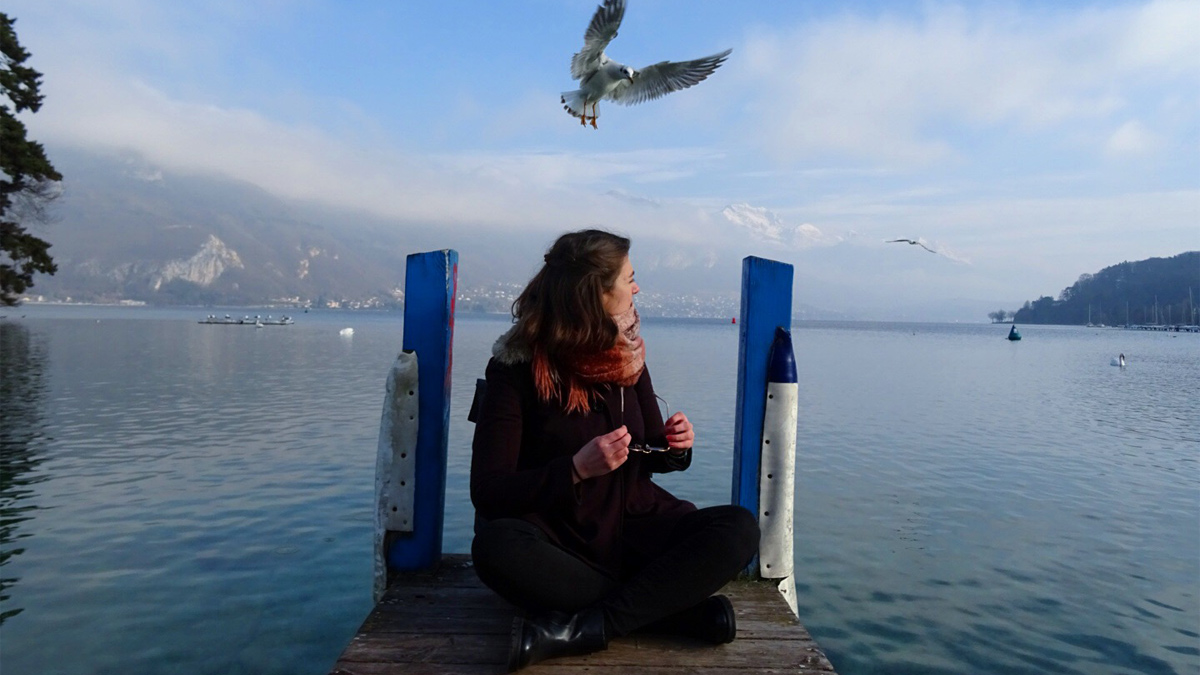 A picture of Ashleigh sitting by Lake Annecy 