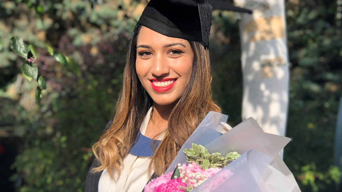 A photo of Shadha holding flowers at her graduation ceremony.