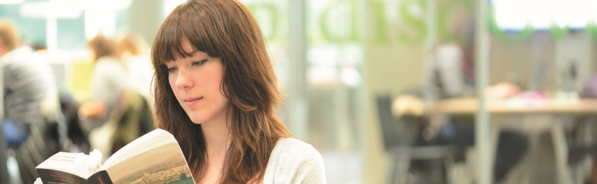 A student reading a book on the 2nd Floor of the Library