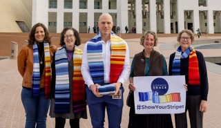 Australian Senator David Pocock receives a climate stripes scarf from members of the Christian and justice group Common Grace