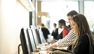 Students working at desktop computers in the University of Reading library.
