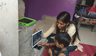 An Indian mother shows her son a tablet screen whilst using the eye tracking app