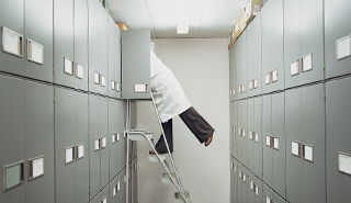 A person in a lab coat reaching into an archive