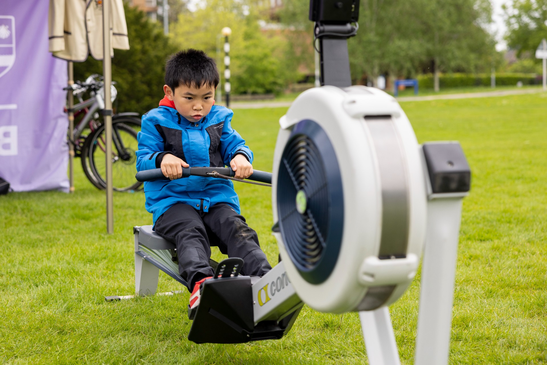 A young Asian boy having a go on a rowing machine