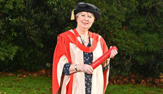 Fiona Talkington in graduation robes holding an honorary degree