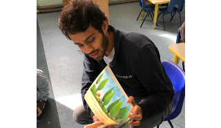 A student volunteer reading a story to nursery children