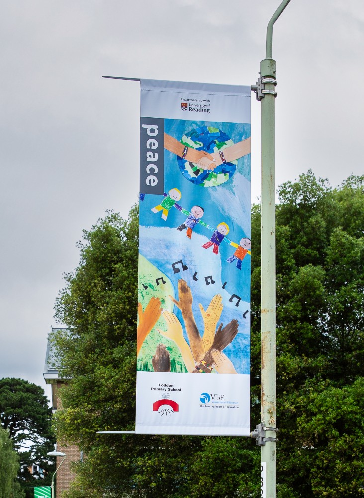 A 'peace' banner, hung from a lamp post, featuring children's artwork