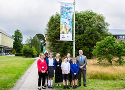 The University Vice-Chancellor stands with teachers and pupils from Loddon Primary School in front of one of the value banners, on the University campus